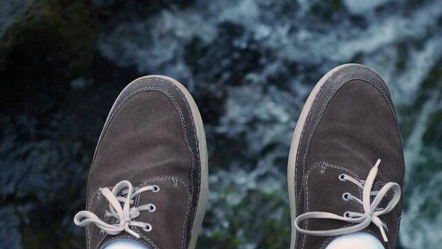Feet above mountain river. Top of view close uo shoes above water surface