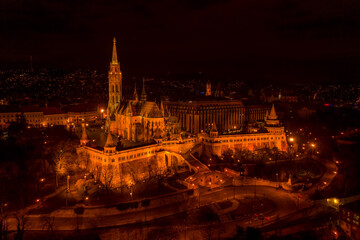 Fototapeta na wymiar Aerial drone shot of Matthias Church with lights on Buda Hill in Budapest evening