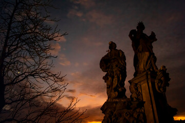 Fototapeta premium In an beautiful sunset, the statues of St. Barbara, St. Margaret and St. Elizabeth on the Charles Bridge in Prague, Czech Republic.