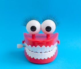 toy with smiling teeth and eyes on blue background as a concept of dentistry and healthy oral cavity and smile