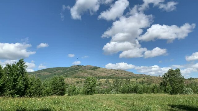 Panoramic view. Beautiful summer landscape. Mountains, blue sky and green fields, forest.