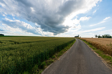 Weg zur Walfahrtskirche Heiligenkreuz bei Kremsmünster in Oberösterreich mit Regenwolken und Getreidefelder