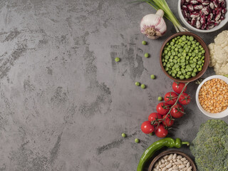 Organic vegetables and assorted beans on a grey background.