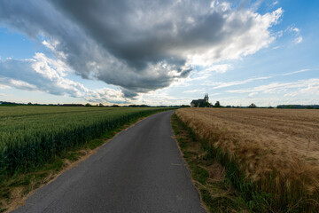 Weg zur Walfahrtskirche Heiligenkreuz bei Kremsmünster in Oberösterreich mit Regenwolken und Getreidefelder