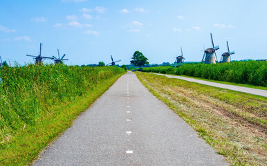 Fototapeta na wymiar Famous tourist attraction Dutch windmills village 'Kinderdijk' in Netherlands, Colorful summer landscape, blue sky and green grass landscape along with the Dutch canals
