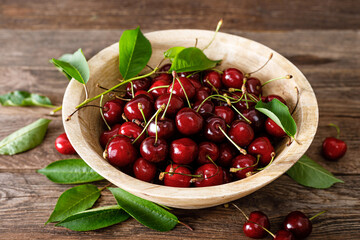 Sweet cherry with leaves in wooden bowl. Fresh ripe cherries. Cherry fruit