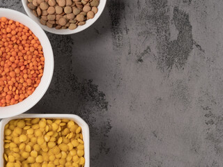 Red, yellow and green lentils on a gray background.