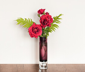 Decorative floral composition of fresh red roses in a vase on the table.