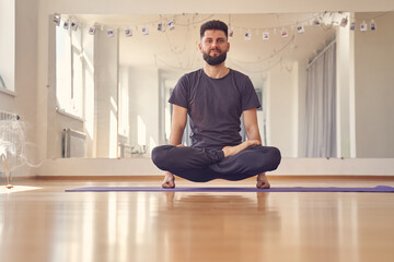 Bearded young man doing lifted lotus or scale pose