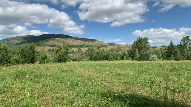 Panoramic view. Beautiful summer landscape. Mountains, blue sky and green fields, forestA group of clouds in the sky
