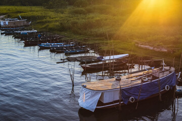 Boats parked on the banks of the Amazon River with golden sunbeam