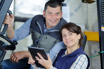 man in forklift talking to woman in white jacket