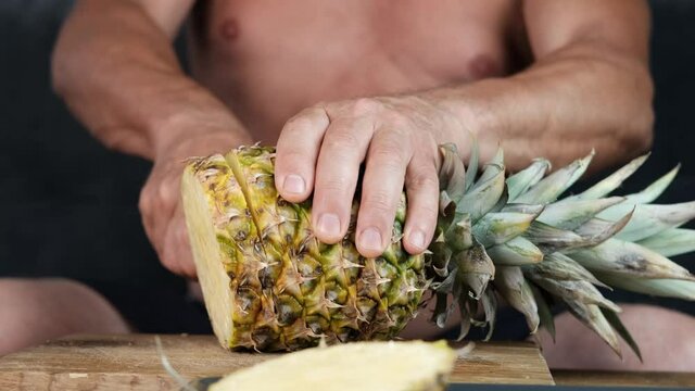 tanned old man decisively slices ripe yellow pineapple, the concept of vegetarian food, relaxation in exotic countries