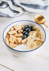 Bowl with amaranth corn pads with banana, blueberry and yogurt on white wooden background. Healthy breakfast and gluten free concept.