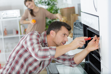 male fixing oven in kitchen