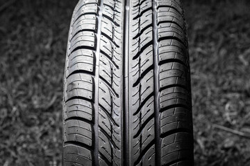 Car tire in dark color. Night shooting. The tread is summer. Light falls from above