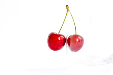 Sweet cherries. Red cherries hang on a transparent glass. A ripe berry on a white background.