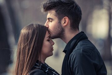 Beautiful young couple having a romantic moment. Handsome man kissing his girlfriend forehead on a sunny day. Concept of Love and relationship