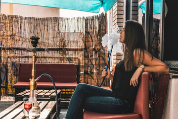 Obraz na płótnie Canvas Young beautiful woman smoking hookah and having a great time