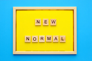 New Normal alphabet letters in wooden frame on blue background. top view, flat lay