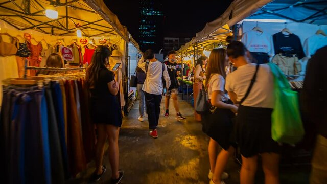 time lapse of Tourist and locals walking and shopping at Rachada Night train market (Talad Rot Fai). market with plenty of shops with colorful canvas roofs at night in Bangkok, Thailand