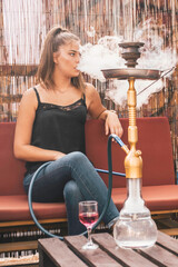 Young beautiful woman smoking hookah and having a great time