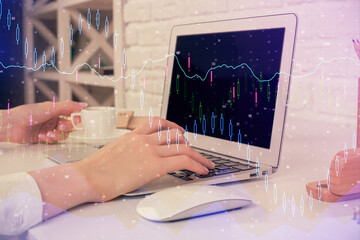 Double exposure of woman hands typing on computer and forex chart hologram drawing. Stock market...