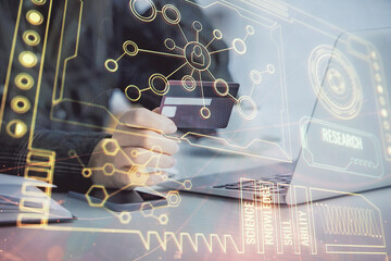 Double exposure of woman on-line shopping holding a credit card and data theme hologram drawing....