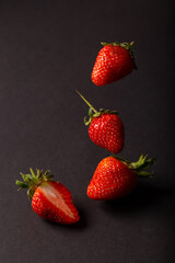 Red strawberries isolated on a black background. Strawberries in flight