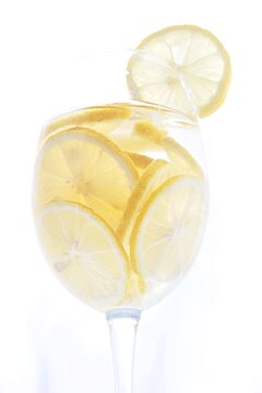 Refreshing lemonade or limoncello cold drink. Sliced fresh ripe lemons rings in a transparent glass