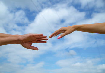 Giving a helping hand. Hands of man and woman on blue sky background. Lending a helping hand. Solidarity, compassion, and charity, rescue. Hands of man and woman reaching to each other, support