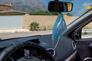 Surgical mask in car rear view mirror