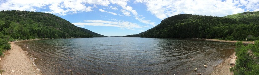 Fototapeta premium Panoramic image of lake with forests and hills surrounding it