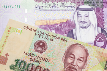 A colorful ten thousand dong note from Vietnam close up in macro with A colorful, five Saudi riyal bank note