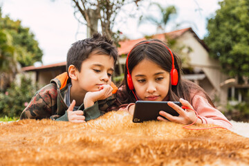 Two kids watching with their smartphones, watching the social media video app, looking at the...