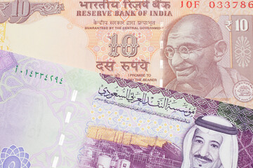 An orange, Indian ten rupee bill, close up with A colorful five riyal note from Saudi Arabia
