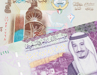 A one quarter dinar from Kuwait close up with a colorful Saudi Arabian five riyal note in macro