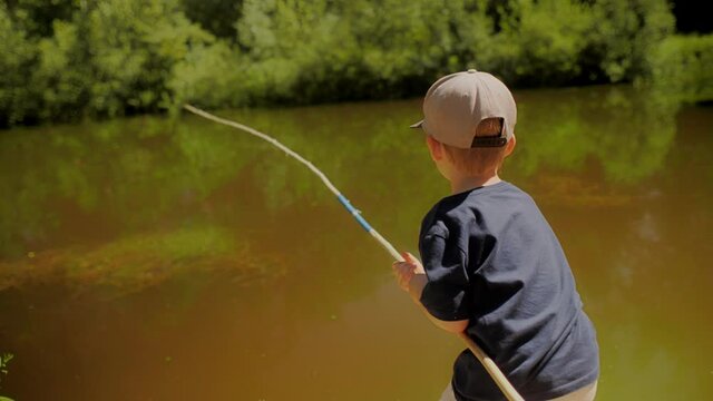 Back view enthusiastic baby boy holding fishing rod trying catching fish