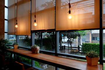 View of blind glass window decoration with lambing hanging on ceiling, Picture of curtains in room with glass and decorated with light bulbs while  raining.