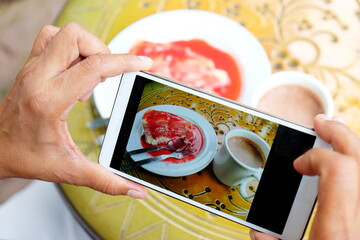 Woman's hand taking photo on mobile phone while sitting in cafe , female looking and using cellphone during breaking and relaxing time