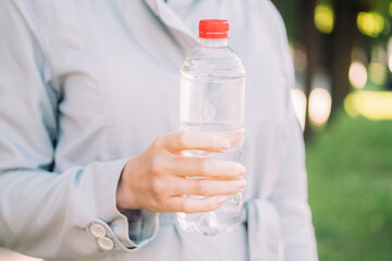 Girl in a coat holds a plastic bottle with mineral water