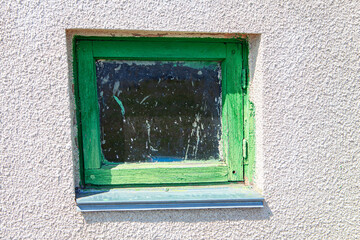Window with green frame . Dirty window leaf of old barn