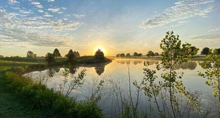 sunrise on golf course hazy sun fog on pond