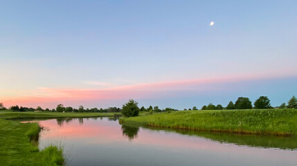 Fototapeta na wymiar early morning on the golf course pond morning moon colorful clouds