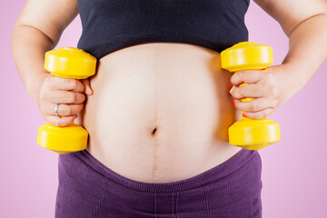 Pregnant woman tummy exercising with two dumbbells