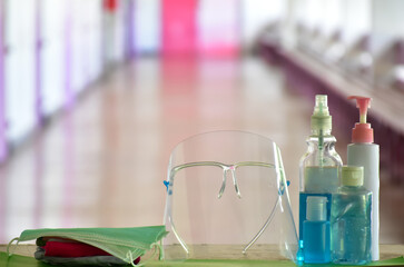 Medical masks, face shield, sanitizer, alcohol gel and hand soap on table in front of balcony to wear and to clean hands to prevent germs and protect coronavirus or covid-19 which is spreading now.