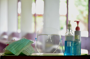 Medical masks, face shield, sanitizer, alcohol gel and hand soap on table in front of balcony to wear and to clean hands to prevent germs and protect coronavirus or covid-19 which is spreading now.
