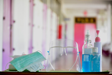Medical masks, face shield, sanitizer, alcohol gel and hand soap on table in front of balcony to wear and to clean hands to prevent germs and protect coronavirus or covid-19 which is spreading now.