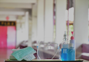 Medical masks, face shield, sanitizer, alcohol gel and hand soap on table in front of balcony to wear and to clean hands to prevent germs and protect coronavirus or covid-19 which is spreading now.