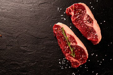 Two raw picanha steaks with spices on a dark background